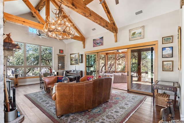 living area featuring visible vents, ceiling fan with notable chandelier, high vaulted ceiling, and a healthy amount of sunlight