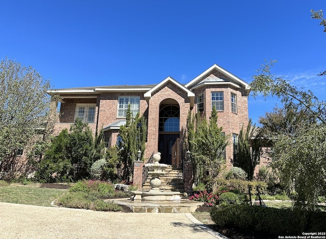 view of front facade featuring stairs, a balcony, and brick siding