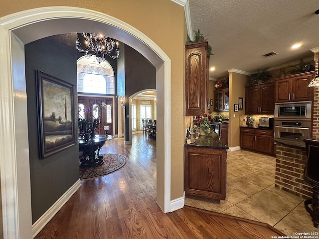 interior space featuring visible vents, a notable chandelier, a textured ceiling, arched walkways, and appliances with stainless steel finishes