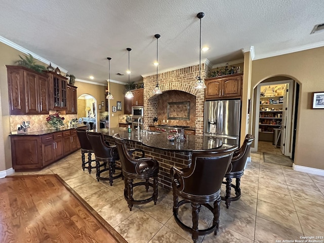 kitchen with a kitchen breakfast bar, arched walkways, glass insert cabinets, and appliances with stainless steel finishes