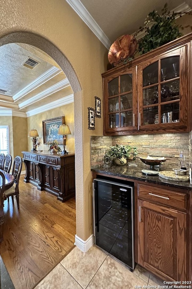 bar with arched walkways, bar, wine cooler, a textured ceiling, and crown molding