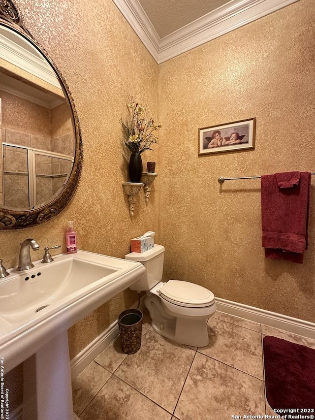 bathroom featuring baseboards, a sink, tile patterned flooring, ornamental molding, and toilet