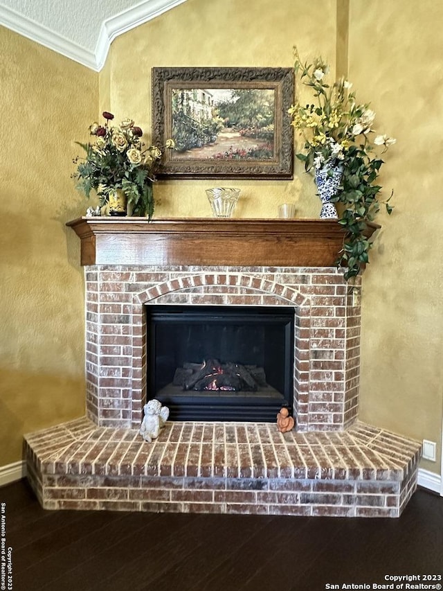 details with a brick fireplace, crown molding, baseboards, and wood finished floors