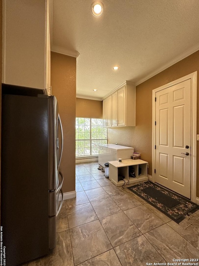 kitchen featuring white cabinetry, freestanding refrigerator, crown molding, light countertops, and baseboards