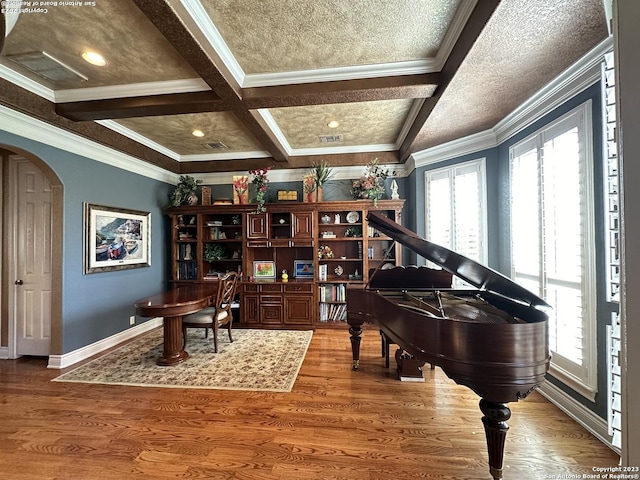 living area with wood finished floors, arched walkways, coffered ceiling, and ornamental molding