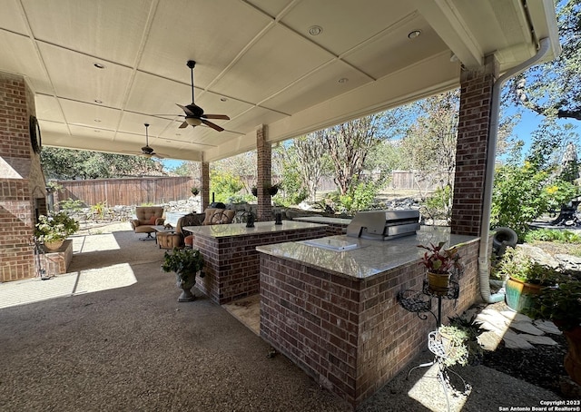 view of patio with ceiling fan, exterior kitchen, fence, and a grill