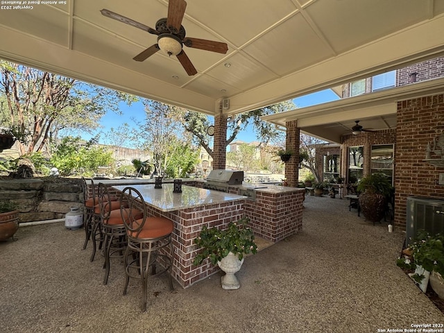 view of patio with outdoor wet bar, area for grilling, and ceiling fan