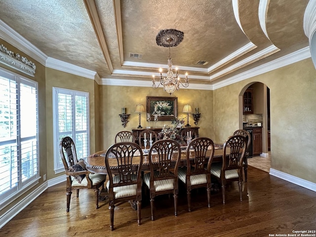 dining room with visible vents, dark wood-style floors, arched walkways, an inviting chandelier, and a raised ceiling