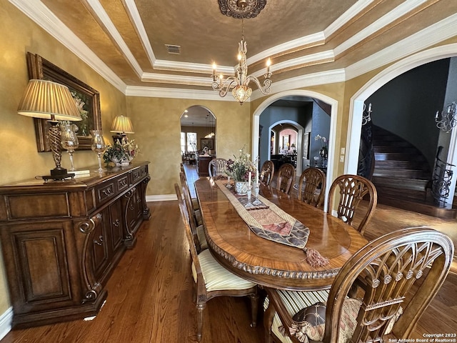 dining area featuring visible vents, a tray ceiling, arched walkways, dark wood-style flooring, and a notable chandelier