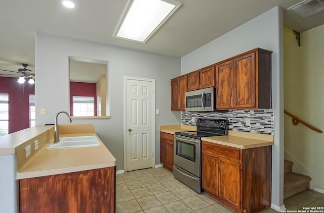 kitchen featuring light tile patterned floors, a sink, decorative backsplash, light countertops, and stainless steel appliances