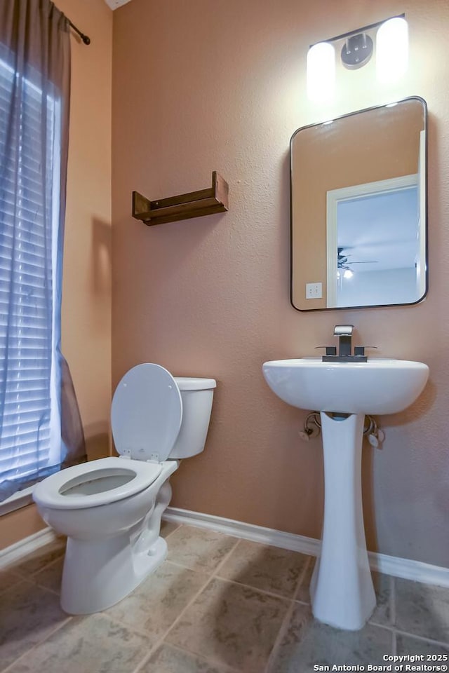 half bathroom featuring tile patterned flooring, toilet, and baseboards