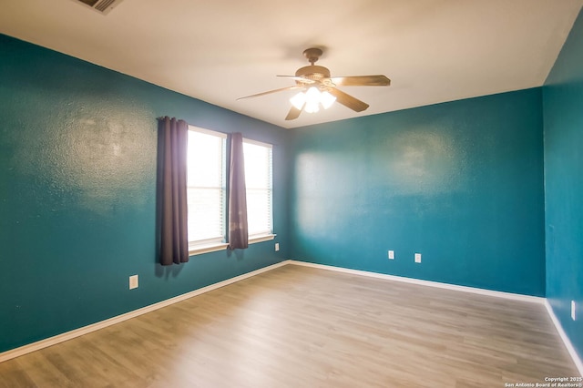 unfurnished room with wood finished floors, baseboards, and ceiling fan