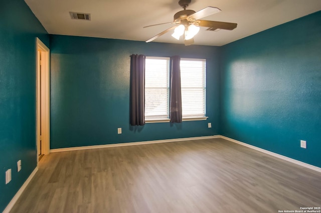 unfurnished room featuring visible vents, baseboards, a ceiling fan, and wood finished floors