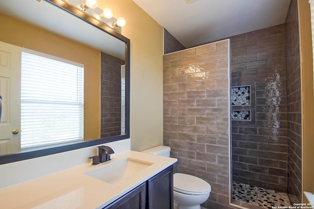 bathroom featuring vanity, toilet, and a tile shower