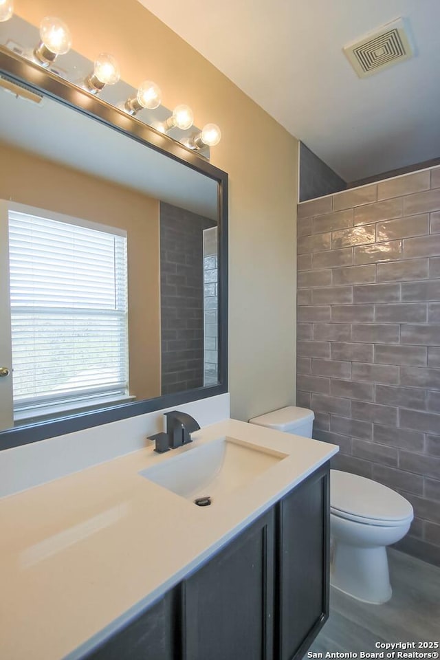 bathroom featuring visible vents, toilet, and vanity