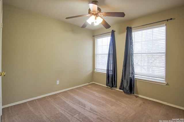 carpeted spare room featuring baseboards and ceiling fan