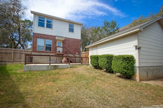 rear view of property with brick siding, fence, and a lawn