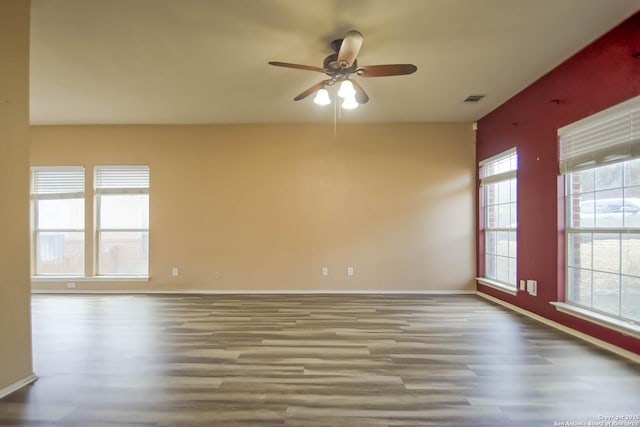 empty room featuring visible vents, baseboards, wood finished floors, and a ceiling fan