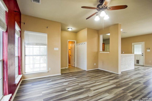 empty room with wood finished floors, a ceiling fan, and baseboards