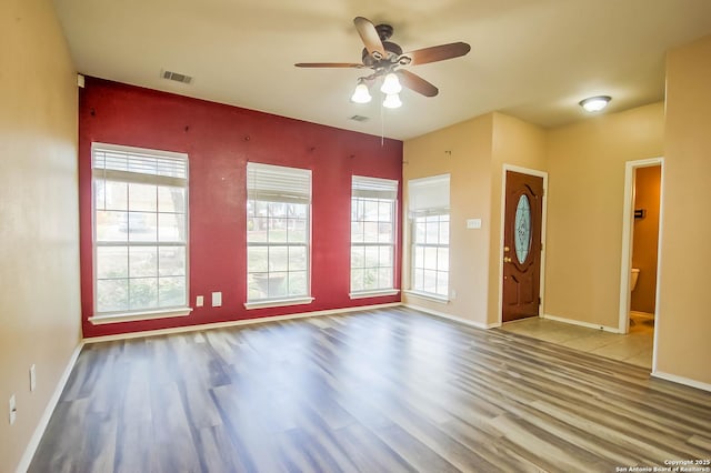 interior space with visible vents, baseboards, ceiling fan, and wood finished floors