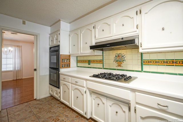 kitchen with stainless steel gas cooktop, light countertops, under cabinet range hood, a textured ceiling, and dobule oven black