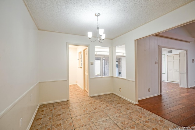 empty room with ornamental molding, a notable chandelier, and a textured ceiling