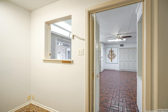 hallway featuring brick floor, visible vents, and baseboards