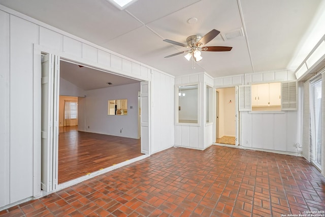 spare room featuring brick floor, a wealth of natural light, and ceiling fan