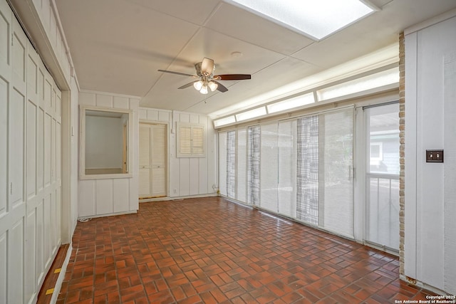 unfurnished room featuring brick floor and ceiling fan