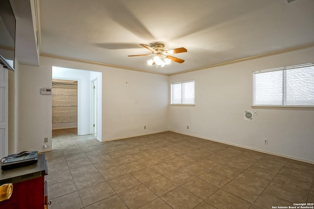 spare room featuring baseboards, crown molding, and a ceiling fan