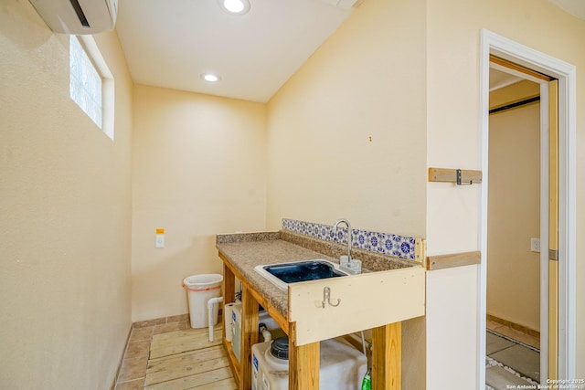 bathroom with recessed lighting, a wall unit AC, and a sink