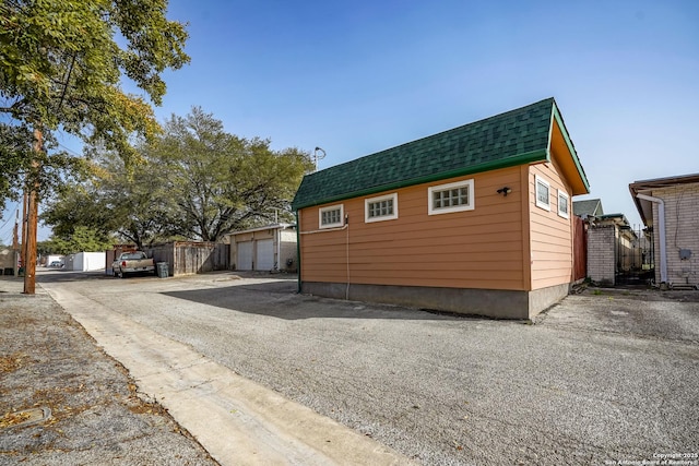 view of front of property with an outdoor structure, fence, and roof with shingles