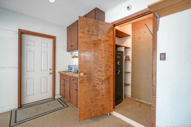 kitchen with stainless steel microwave, concrete flooring, and brown cabinetry