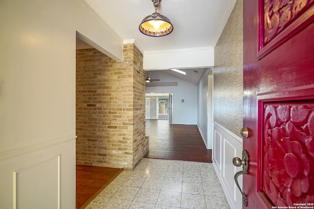 corridor featuring lofted ceiling, ornamental molding, and brick wall