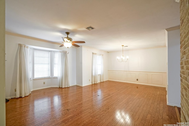 empty room with visible vents, wood-type flooring, a healthy amount of sunlight, and ornamental molding