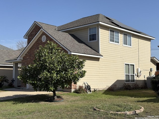 view of side of property with roof mounted solar panels, a lawn, and roof with shingles