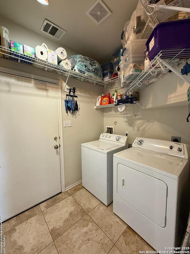 washroom featuring washer and clothes dryer, visible vents, laundry area, and light tile patterned floors