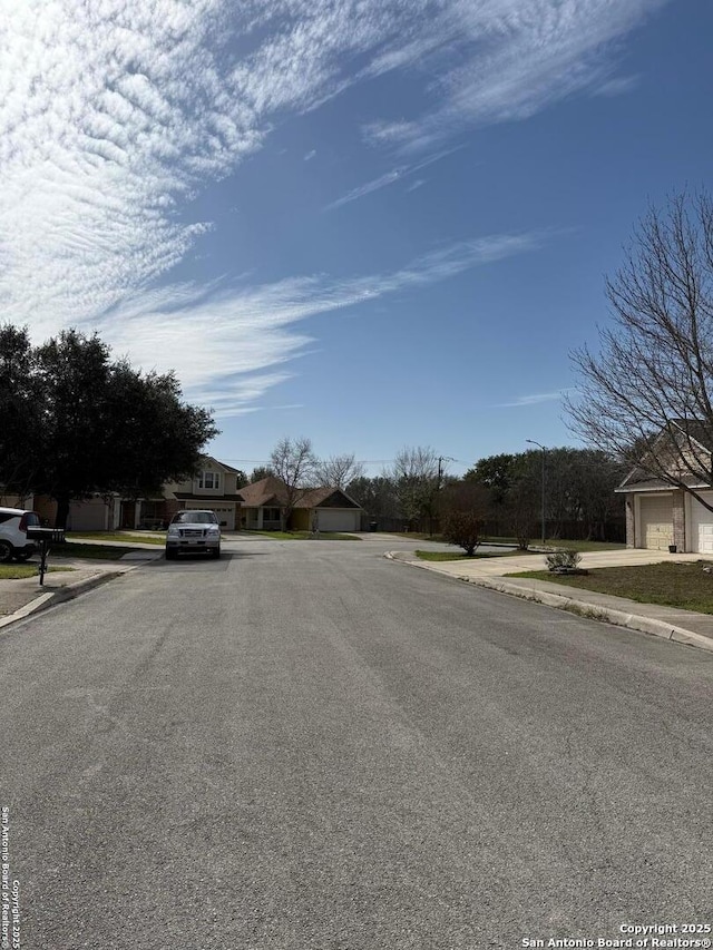 view of street with sidewalks, a residential view, curbs, and street lights