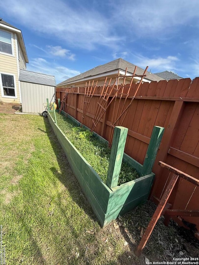 view of yard featuring an outbuilding, a garden, fence, and a shed