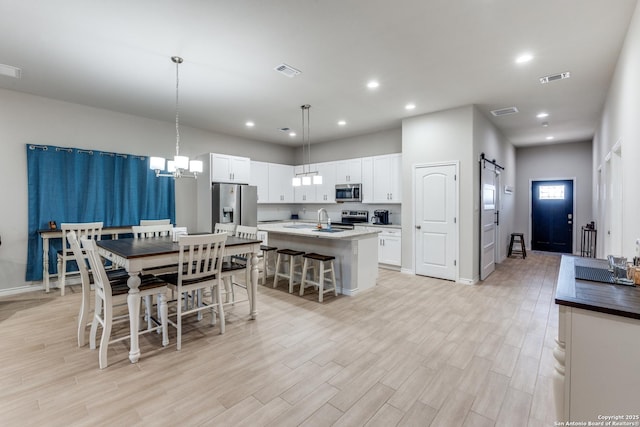 dining room featuring visible vents, recessed lighting, light wood-type flooring, and a barn door