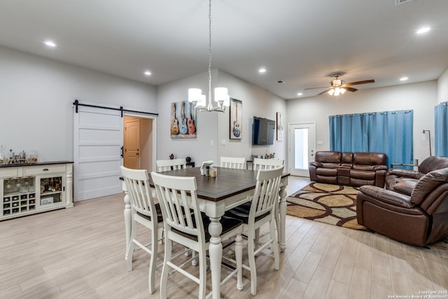 dining room featuring a barn door, recessed lighting, and light wood-type flooring