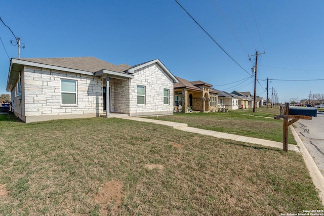 single story home with a front yard, stone siding, and roof with shingles