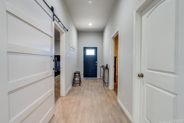 doorway with recessed lighting, a barn door, baseboards, and light wood finished floors