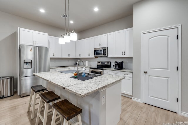 kitchen with a breakfast bar, appliances with stainless steel finishes, and white cabinetry