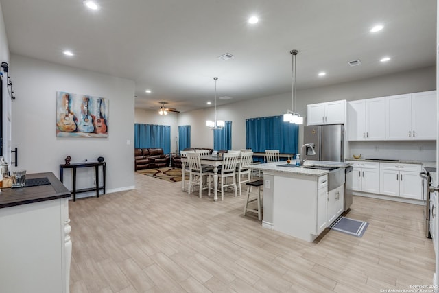 kitchen featuring light wood finished floors, visible vents, open floor plan, and appliances with stainless steel finishes