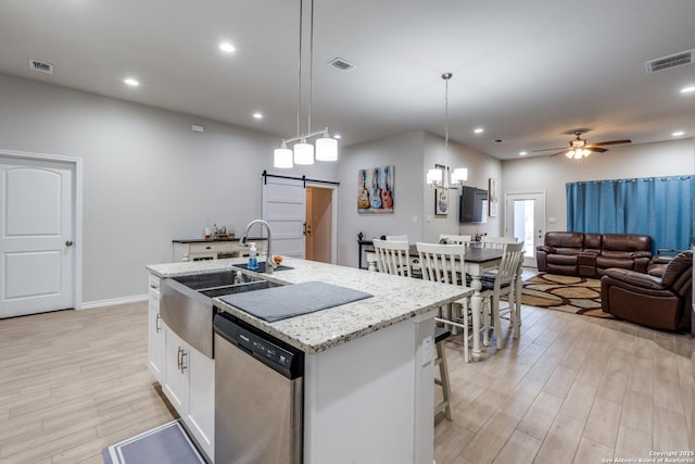 kitchen with stainless steel dishwasher, a barn door, visible vents, and a sink