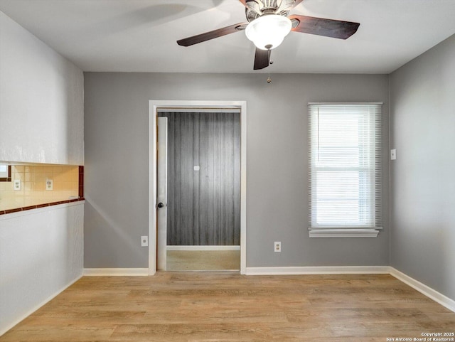 unfurnished room with baseboards, light wood-style flooring, and a ceiling fan