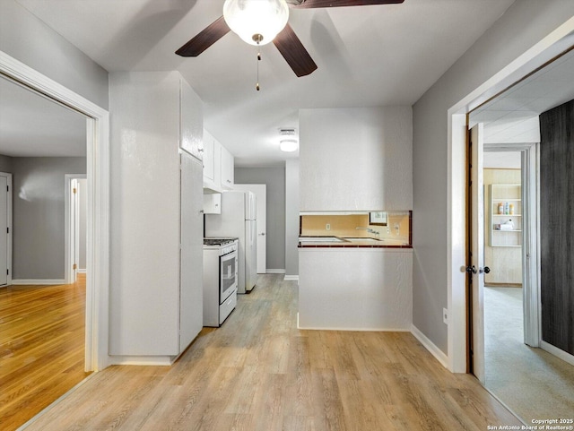 kitchen featuring white gas range, white cabinetry, light wood-style floors, and a ceiling fan