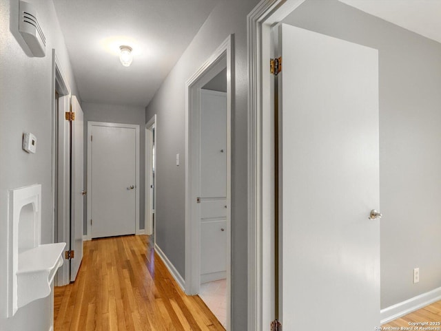 hall with light wood-style flooring and baseboards