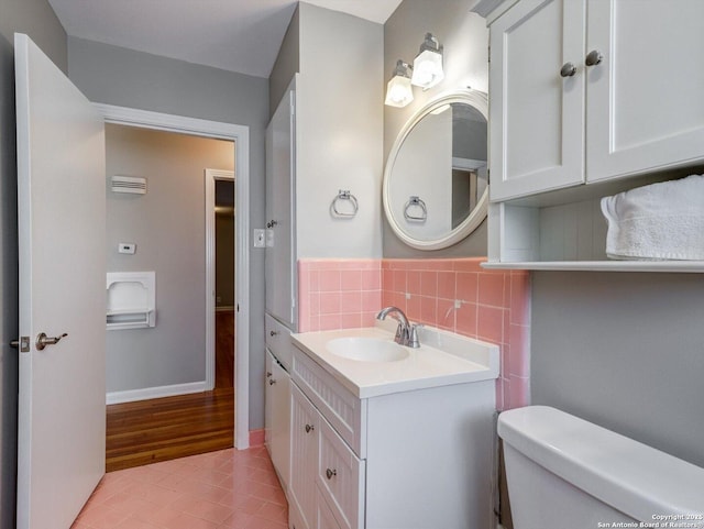 half bath with vanity, baseboards, tile patterned floors, toilet, and tasteful backsplash